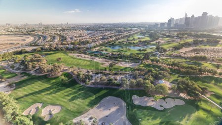 Golf course and Jumeirah lake towers skyscrapers before sunset timelapse, Dubai, United Arab Emirates. Aerial view from Greens district.