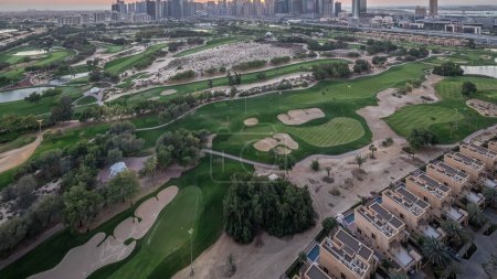 Foto de Torres lago Jumeirah y Dubai Marina rascacielos y campo de golf día a noche timelapse transición, Dubai, Emiratos Árabes Unidos. Vista aérea desde el distrito de Greens después del atardecer - Imagen libre de derechos