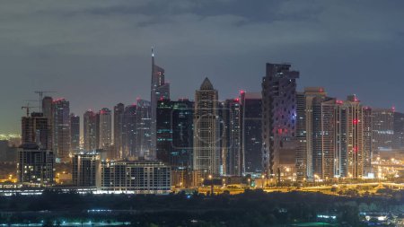 Jumeirah lake towers skyscrapers and golf course night to day transition timelapse, Dubai, United Arab Emirates. Aerial view from Greens district before sunrise