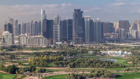 Jumeirah lake towers skyscrapers and golf course morning timelapse, Dubai, United Arab Emirates. Aerial view from Greens district. Green lawn and cloudy sky