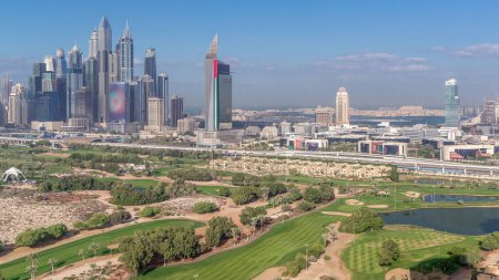 Foto de Dubai Marina and media city rascacielos y campo de golf timelapse mañana, Dubai, Emiratos Árabes Unidos. Vista aérea desde el distrito de Greens. Césped verde y cielo nublado - Imagen libre de derechos