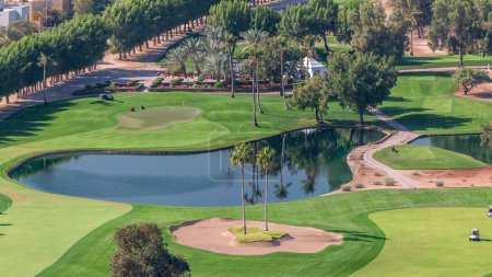 Téléchargez les photos : Paysage de terrain de golf vert avec arbres et lacs timelapse aérienne. Dubaï, EAU. Vue de dessus du quartier des Verts près de la marina de Dubaï - en image libre de droit