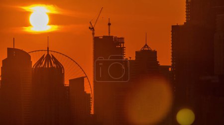 Photo for Dubai Marina skyscrapers from golf course sunset timelapse, Dubai, United Arab Emirates. Aerial view from Greens district. Close up view and orange sky - Royalty Free Image