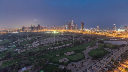 Golf course with Dubai Marina and JLT skyscrapers night to day transition timelapse, Dubai, United Arab Emirates. Aerial view from Greens district before sunrise