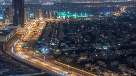Luftaufnahme von Mehrfamilienhäusern und Villen in Dubai City im Zeitraffer in der Nähe des Jumeirah Lake Towers District, Vereinigte Arabische Emirate. Blick von oben auf Wolkenkratzer mit Verkehr auf der Autobahn