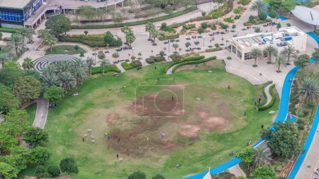 Téléchargez les photos : Un parc public paysager à Jumeirah Lakes Towers timelapse aérien, un quartier résidentiel populaire vers l'extrémité sud de Dubaï. Pelouse verte et paumes d'en haut
. - en image libre de droit