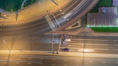 Tráfico en la carretera en Jumeirah Lakes Towers distrito aéreo noche timelapse. Intersección con los coches en JLT desde arriba
