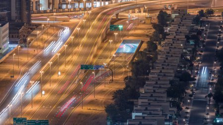 Traffic on the road in Jumeirah Lakes Towers district aerial night timelapse. Intersection and overpass with cars on JLT from above