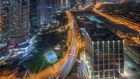 Téléchargez les photos : Jumeirah Lake Towers quartier résidentiel nuit aérienne timelapse près de Dubai Marina. Des gratte-ciels modernes éclairés et le trafic d'en haut - en image libre de droit
