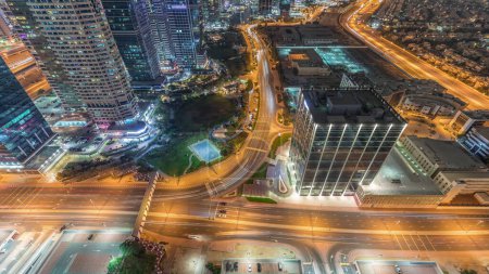 Photo for Traffic on the road in Jumeirah Lakes Towers district aerial night timelapse. Intersection with cars on JLT with park from above - Royalty Free Image