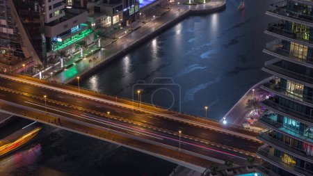 Photo for Waterfront promenade with traffic on a bridge in Dubai Marina aerial night timelapse. Boats and yachts floating on canal. Dubai, United Arab Emirates - Royalty Free Image