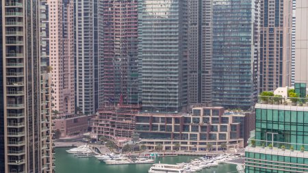Téléchargez les photos : Vue aérienne des gratte-ciel résidentiels et de bureau de Dubai Marina avec timelapse en bord de mer. Bateaux et yachts flottants - en image libre de droit