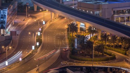 Téléchargez les photos : Vue aérienne de la rue de la marina de Dubaï avec site de construction sur fond timelapse de nuit. Trafic sur une route et un pont - en image libre de droit