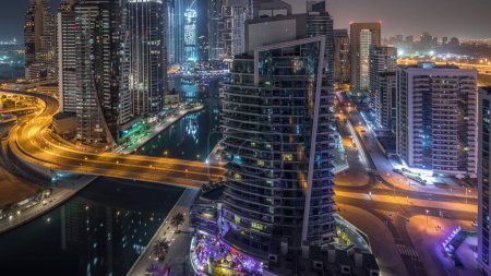 Téléchargez les photos : Vue aérienne panoramique sur les gratte-ciel résidentiels et de bureau de Dubai Marina avec circulation sur un pont et front de mer nuit au jour transition timelapse avant le lever du soleil. Bateaux et yachts flottants - en image libre de droit