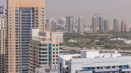 Téléchargez les photos : Terrain de golf de Dubaï avec un paysage urbain des Verts et des districts tecom à l'arrière-plan intemporel aérien. Vue de dessus depuis la marina de Dubaï - en image libre de droit