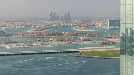 Téléchargez les photos : Vue aérienne de Palm Jumeirah homme fait île du district de JBR avant le coucher du soleil timelapse. Dubaï, EAU. Site de construction d'un nouveau terminal portuaire avec bateaux et yachts - en image libre de droit