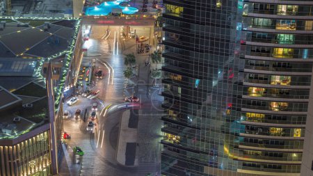 Téléchargez les photos : Vue d'ensemble du front de mer Jumeirah Beach Residence JBR skyline timelapse de nuit aérienne avec des gratte-ciel éclairés. Commerces, restaurants et autres divertissements d'en haut avec la circulation - en image libre de droit