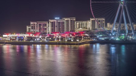 Téléchargez les photos : Bluewaters Island à Dubaï timelapse de nuit aérienne avec des bâtiments éclairés. Yachts et bateaux de passage. Île artificielle située au large de la côte de Jumeirah Beach Residence - en image libre de droit