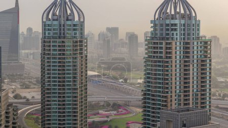 Aerial top view of Dubai Marina morning timelapse. Golf corce and greens district on background after sunrise in Dubai, UAE. Modern towers and traffic on the road