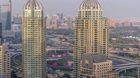 Aerial top view of Dubai Marina evening timelapse. Skyscrapers during sunset in Dubai, UAE. Golf course on a background. Modern towers and traffic on the road