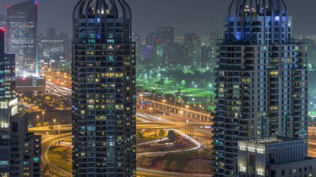 Téléchargez les photos : Vue aérienne du timelapse de transition nocturne de Dubai Marina. Terrain de golf sur fond à Dubaï, EAU. Tours modernes éclairées et circulation sur la route - en image libre de droit