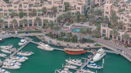 Vista superior aérea de Dubai Marina día a noche timelapse transición. Paseo marítimo y canal con yates flotantes y barcos después del atardecer en Dubai, Emiratos Árabes Unidos. Edificios iluminados y fuente
