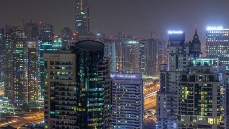 Photo for Aerial top view of Dubai Marina and JLT night timelapse. Skyscrapers from above in Dubai, UAE. Illuminated modern towers and traffic on the road - Royalty Free Image