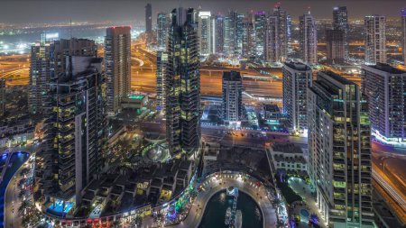 Téléchargez les photos : Vue aérienne du ciel de Dubai Marina nuit timelapse. Promenade et canal avec des yachts flottants et des bateaux à Dubaï, EAU. Tours modernes éclairées et circulation sur la route - en image libre de droit