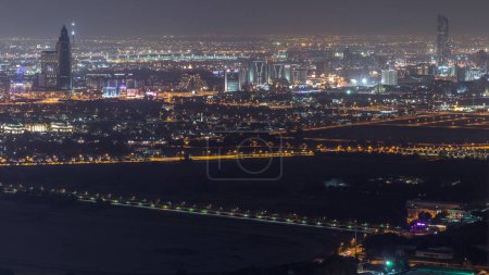 Foto de Vista aérea a Creek y zabeel distrito noche timelapse con el tráfico y el edificio desde el centro de Dubai. Deira en un segundo plano. Rascacielos iluminados - Imagen libre de derechos