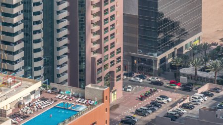 Téléchargez les photos : Parking avec piscine sur le toit vue de dessus timelapse, vue aérienne sur le quartier financier. Les gens se détendent. Dubai, Émirats arabes unis - en image libre de droit