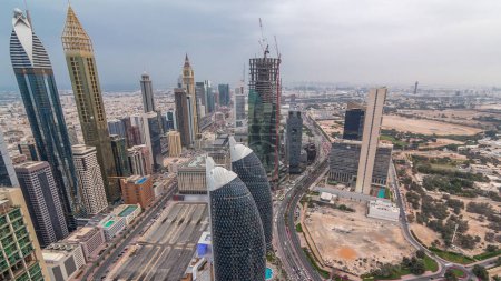 Foto de Skyline of the buildings near Sheikh Zayed Road and DIFC aerial day to night in Dubai, UAE. Modernas torres y rascacielos con obras de construcción en el centro financiero y el centro después del atardecer - Imagen libre de derechos