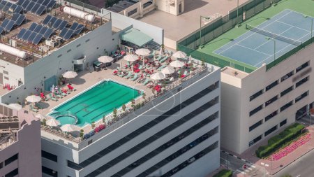 Téléchargez les photos : Parking avec piscine sur le toit vue de dessus timelapse, vue aérienne sur le quartier financier. Les gens se détendent. Dubai, Émirats arabes unis - en image libre de droit
