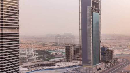 Téléchargez les photos : Appartements résidentiels et bureaux à Jumeirah Lake Towers quartier timelapse à Dubaï. Vue panoramique aérienne d'en haut avec gratte-ciel modernes, villas et chantier de construction - en image libre de droit