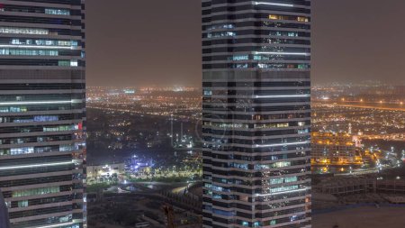 Téléchargez les photos : Des immeubles de bureaux à Jumeirah Lake Towers quartier timelapse de nuit avec des lumières clignotantes dans les fenêtres à Dubaï. Vue aérienne d'en haut avec des gratte-ciel modernes - en image libre de droit