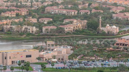 Téléchargez les photos : Vue aérienne des maisons d'appartements et villas avec mosquée et parking dans la ville de Dubaï timelapse près du quartier Jumeirah Lake Towers, Émirats arabes unis. Vue de dessus depuis le gratte-ciel - en image libre de droit