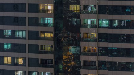 Foto de Vista nocturna del apartamento exterior timelapse edificio. Rascacielos de gran altura con luces parpadeantes en ventanas con personas moviéndose dentro - Imagen libre de derechos