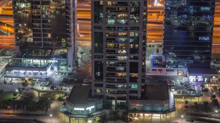Foto de Edificios residenciales y de oficinas en Jumeirah lago torres distrito por la mañana timelapse con tiendas, restaurantes y pasarelas en Dubai. Vista panorámica aérea desde arriba con rascacielos modernos y tráfico - Imagen libre de derechos