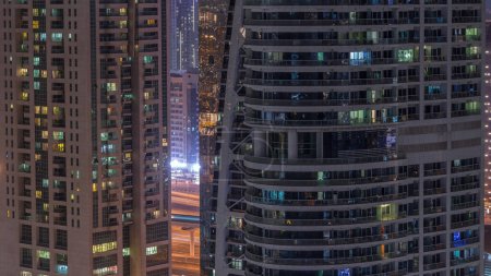Foto de Edificios residenciales y de oficinas en Jumeirah lago torres distrito noche timelapse con luces parpadeantes en las ventanas de Dubai. Vista aérea desde arriba con rascacielos modernos - Imagen libre de derechos