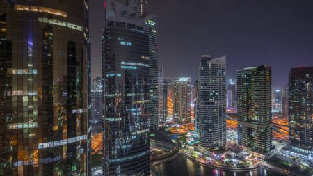 Edificios residenciales y de oficinas en Jumeirah lago torres distrito noche timelapse en Dubai. Vista panorámica aérea desde arriba con rascacielos modernos
