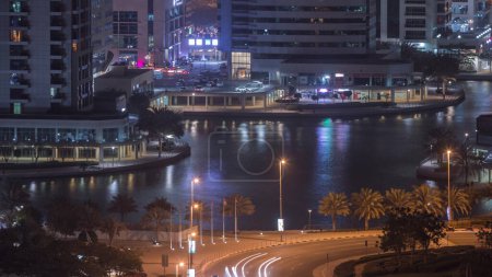 Téléchargez les photos : Des immeubles résidentiels et de bureaux dans le quartier Jumeirah Lake Towers Night Timelapse avec des boutiques, des restaurants et des allées à Dubaï. Vue panoramique aérienne d'en haut avec des gratte-ciel modernes - en image libre de droit