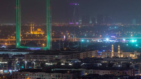 Foto de Dubai Marco con mezquita Zabeel Masjid iluminado por la noche timelapse. Vista aérea desde arriba durante la tormenta de arena. El marco es un hito arquitectónico en Zabeel Park
. - Imagen libre de derechos