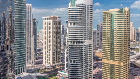 Apartamentos y oficinas residenciales en Jumeirah lago torres distrito timelapse en Dubai. Vista aérea desde arriba con rascacielos modernos y nubes en el cielo azul
