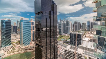 Téléchargez les photos : Appartements résidentiels et bureaux à Jumeirah Lake Towers quartier timelapse à Dubaï. Vue panoramique aérienne d'en haut avec des gratte-ciel modernes et des nuages sur ciel bleu - en image libre de droit