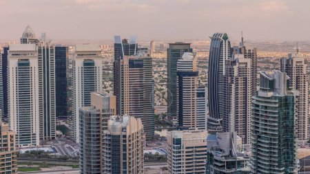 Photo for Dubai Marina skyscrapers and jumeirah lake towers view from the top aerial timelapse in the United Arab Emirates. Traffic on a road - Royalty Free Image