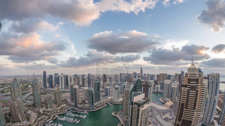 Dubai Marina skyscrapers and jumeirah lake towers panoramic view from the top aerial day to night transition timelapse in the United Arab Emirates. Traffic on a road