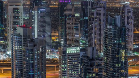 Téléchargez les photos : Dubai Marina illuminé gratte-ciel et jumeirah lac tours vue depuis le haut timelapse de nuit aérienne dans les Émirats arabes unis. Trafic sur une route - en image libre de droit