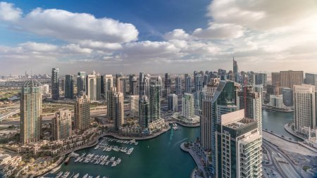 Photo for Dubai Marina skyscrapers and jumeirah lake towers panoramic view from the top aerial timelapse with yachts and boats in the United Arab Emirates. Traffic on a road with cloudy sky - Royalty Free Image