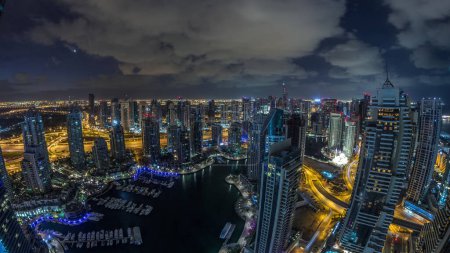 Foto de Dubai Marina rascacielos iluminados y torres de lago jumeirah vista panorámica desde la parte superior aérea noche al día timelapse transición en los Emiratos Árabes Unidos. Tráfico por carretera - Imagen libre de derechos
