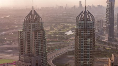 Photo for Dubai Marina skyscrapers and jumeirah lake towers view during sunrise from the top aerial morning timelapse in the United Arab Emirates. Traffic on roads and junction with haze - Royalty Free Image