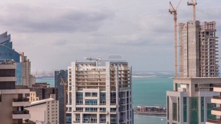 Téléchargez les photos : Bâtiments modernes sur la marina de Dubaï et JBR avec grues sur le chantier de construction timelapse aérien à Dubaï, Émirats arabes unis. Ciel nuageux le matin - en image libre de droit